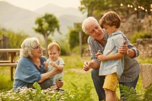 Two grandparents playing with children in a field.