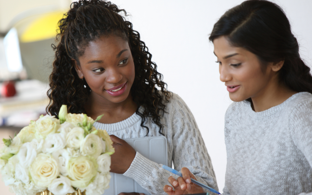 Two women talking about information on an ipad that one woman is holding.